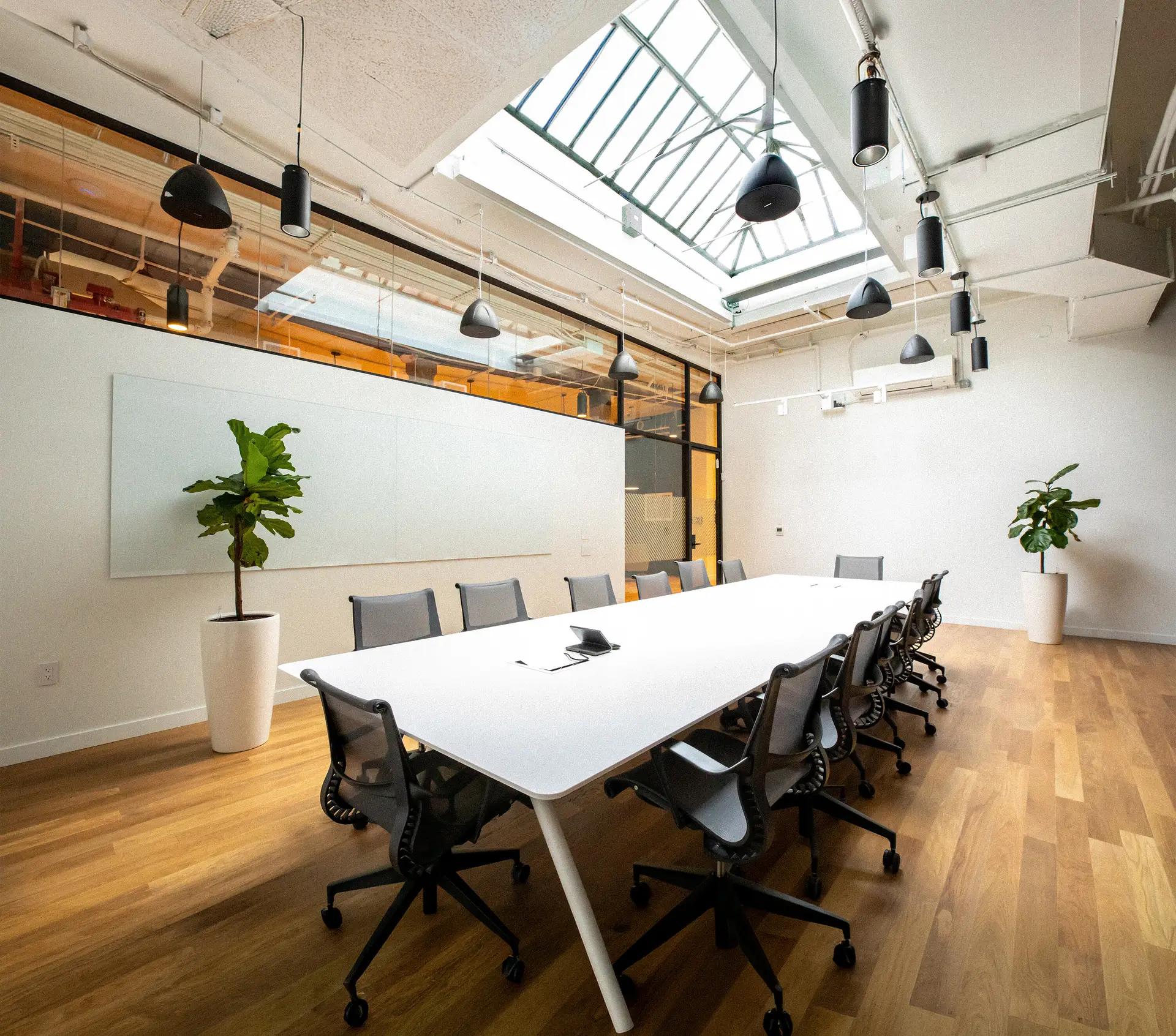 Konrad office — a long communal table and chairs beside floor-to-ceiling windows overlooking the city skyline