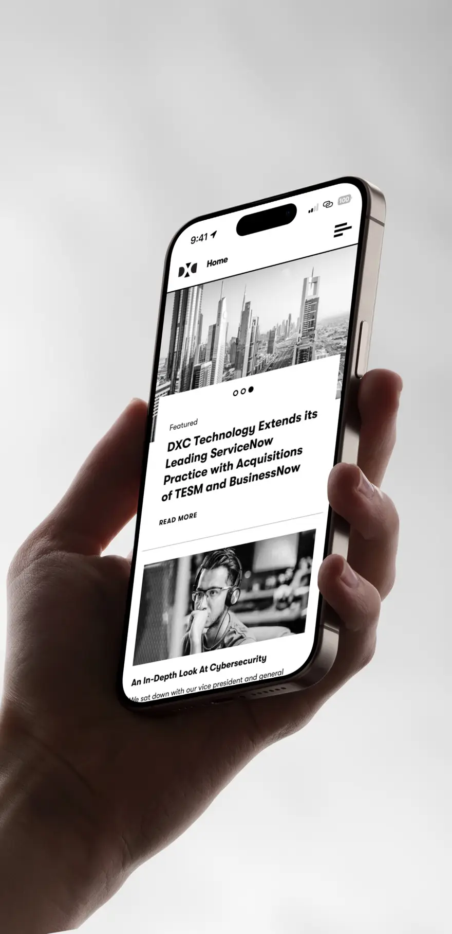 Hand holding a phone showing the DXC.technology news feed with a featured article