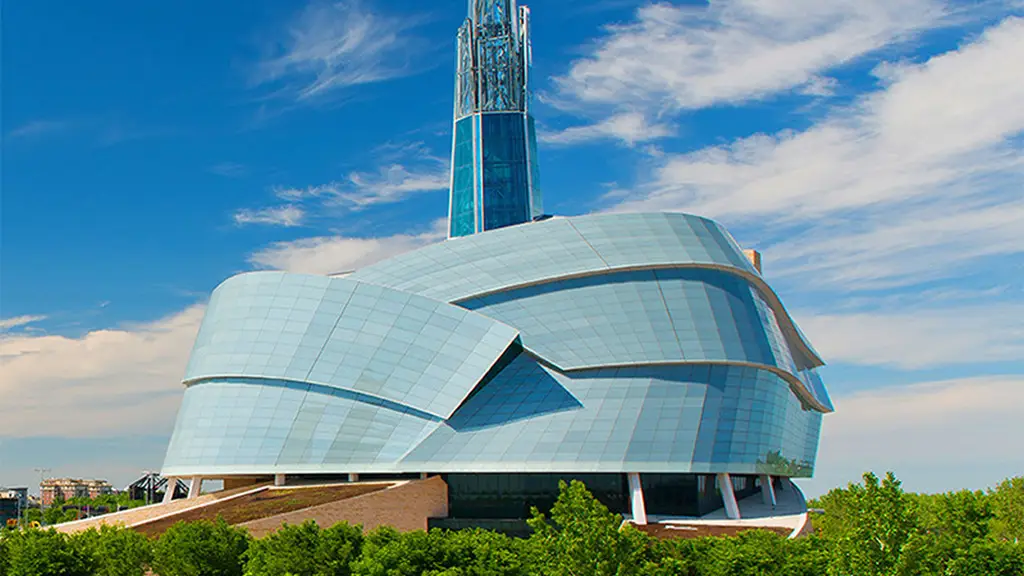 A modern building with a curved glass-and-steel facade against a blue sky