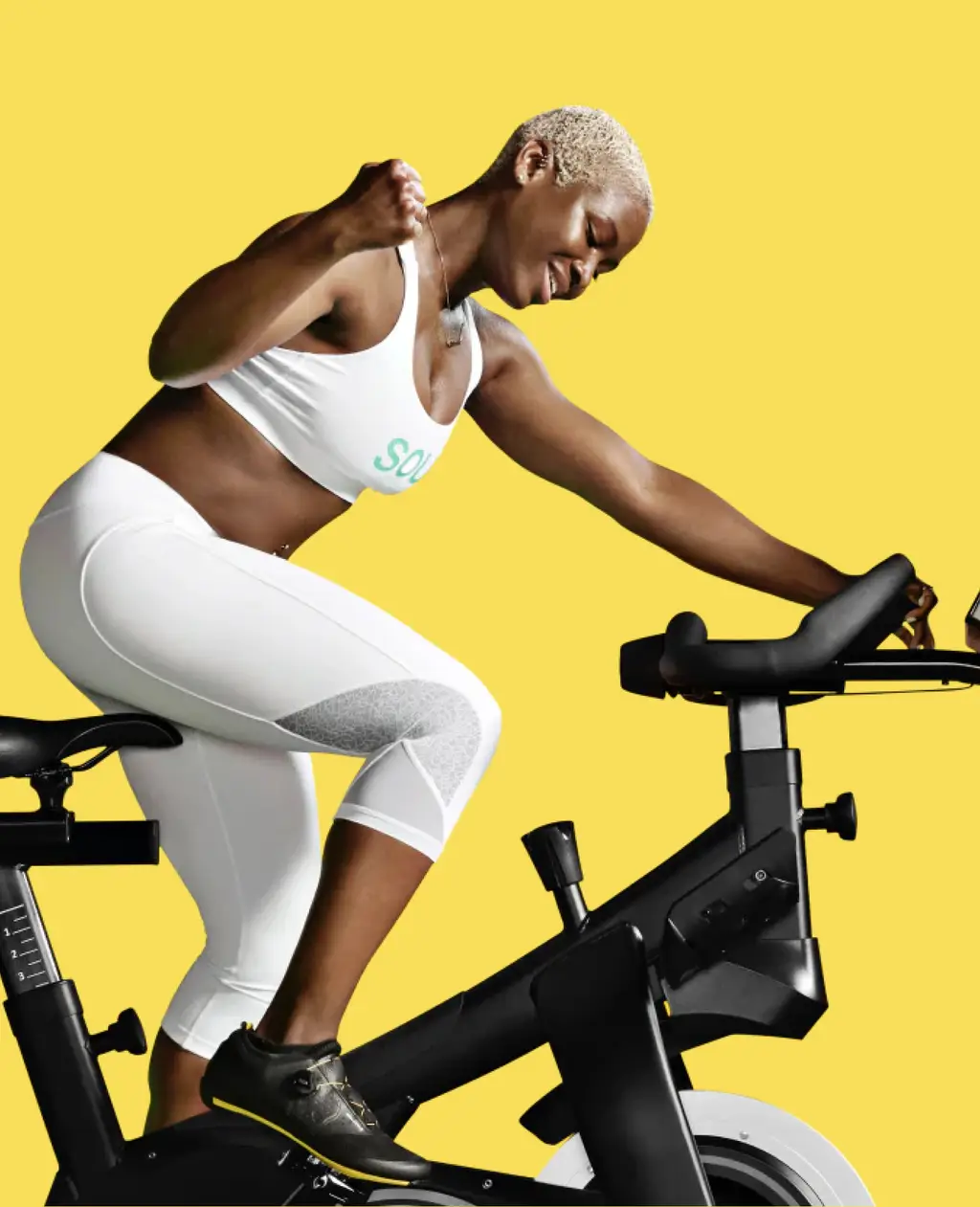 Rider on the SoulCycle at-home bike against a yellow backdrop