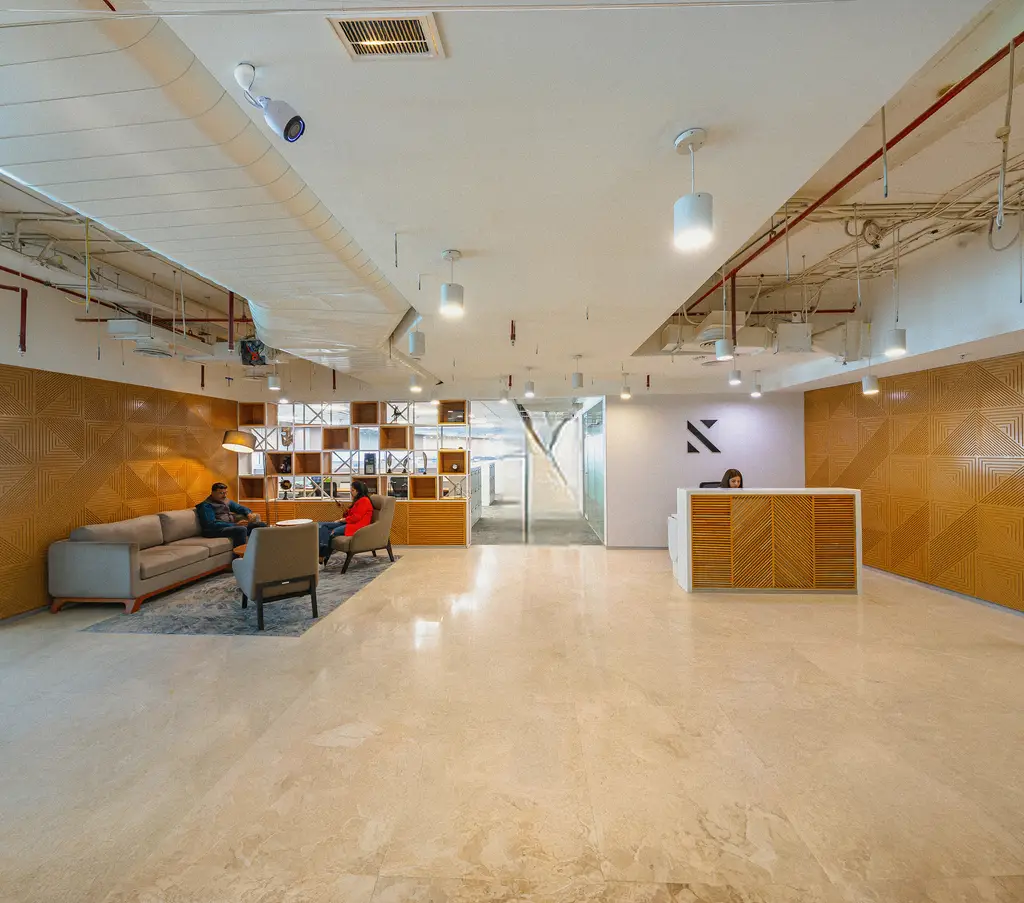 Konrad’s Gurgaon office lounge with grid shelving, armchairs and warm lighting
