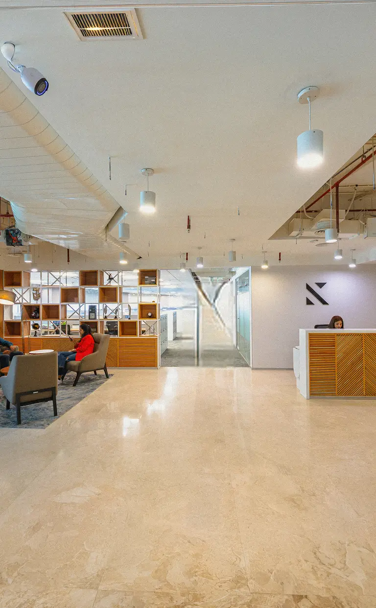 Konrad’s Gurgaon office lounge with grid shelving, armchairs and warm lighting