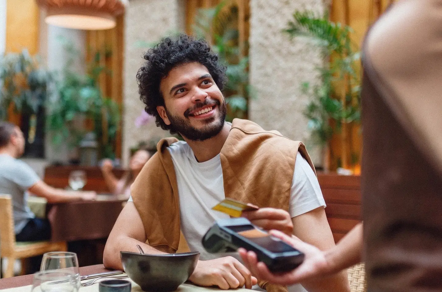 Smiling young man holding a bank card while seated in a café