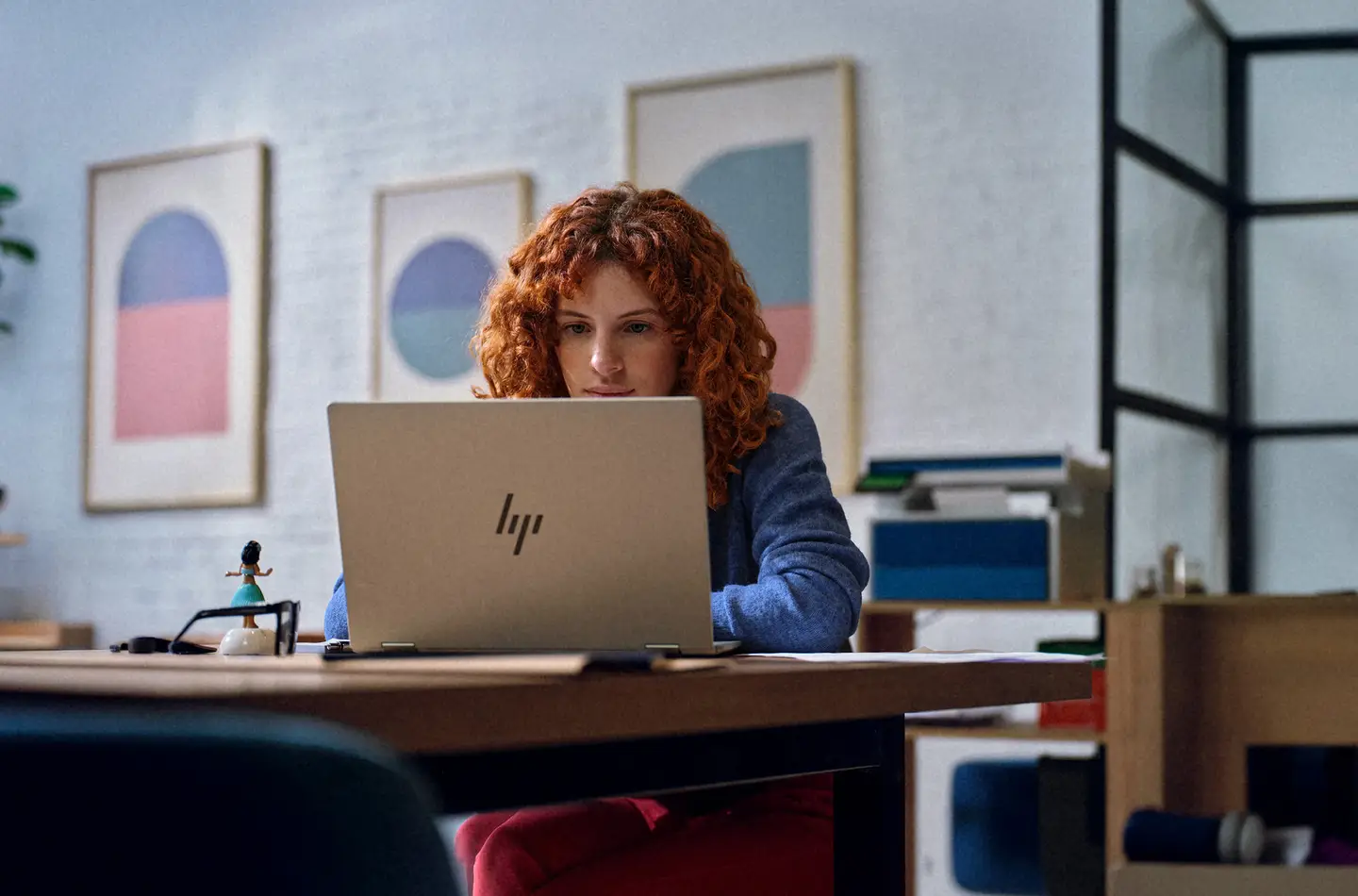 Woman with curly red hair working at an HP laptop