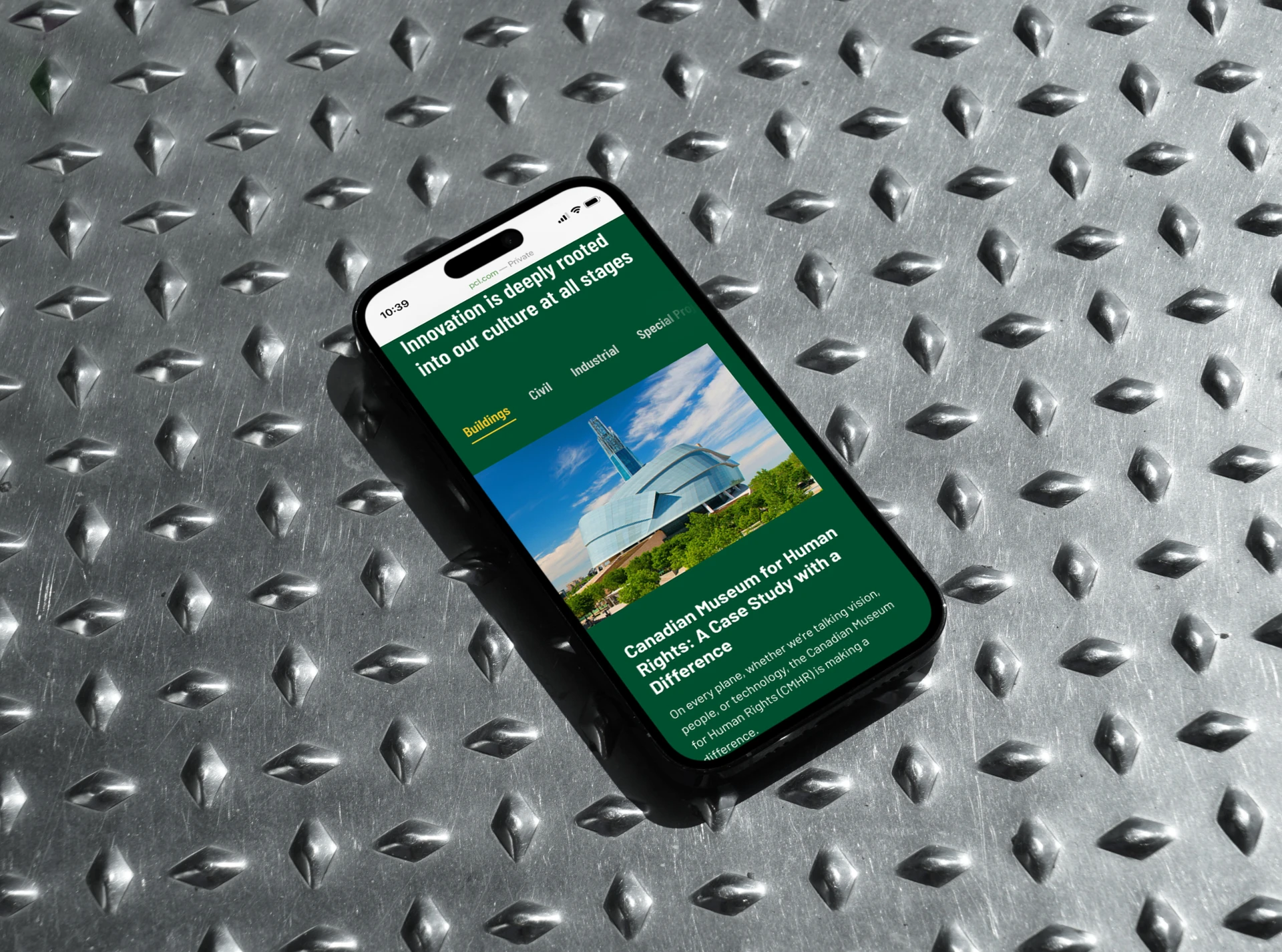 Phone on a diamond-plate steel surface showing the PCL website