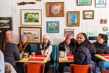 Team members seated at café tables beneath walls covered in framed pictures