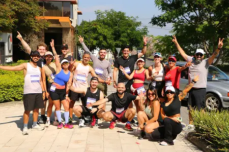 A large group of team members celebrating outdoors with their arms raised