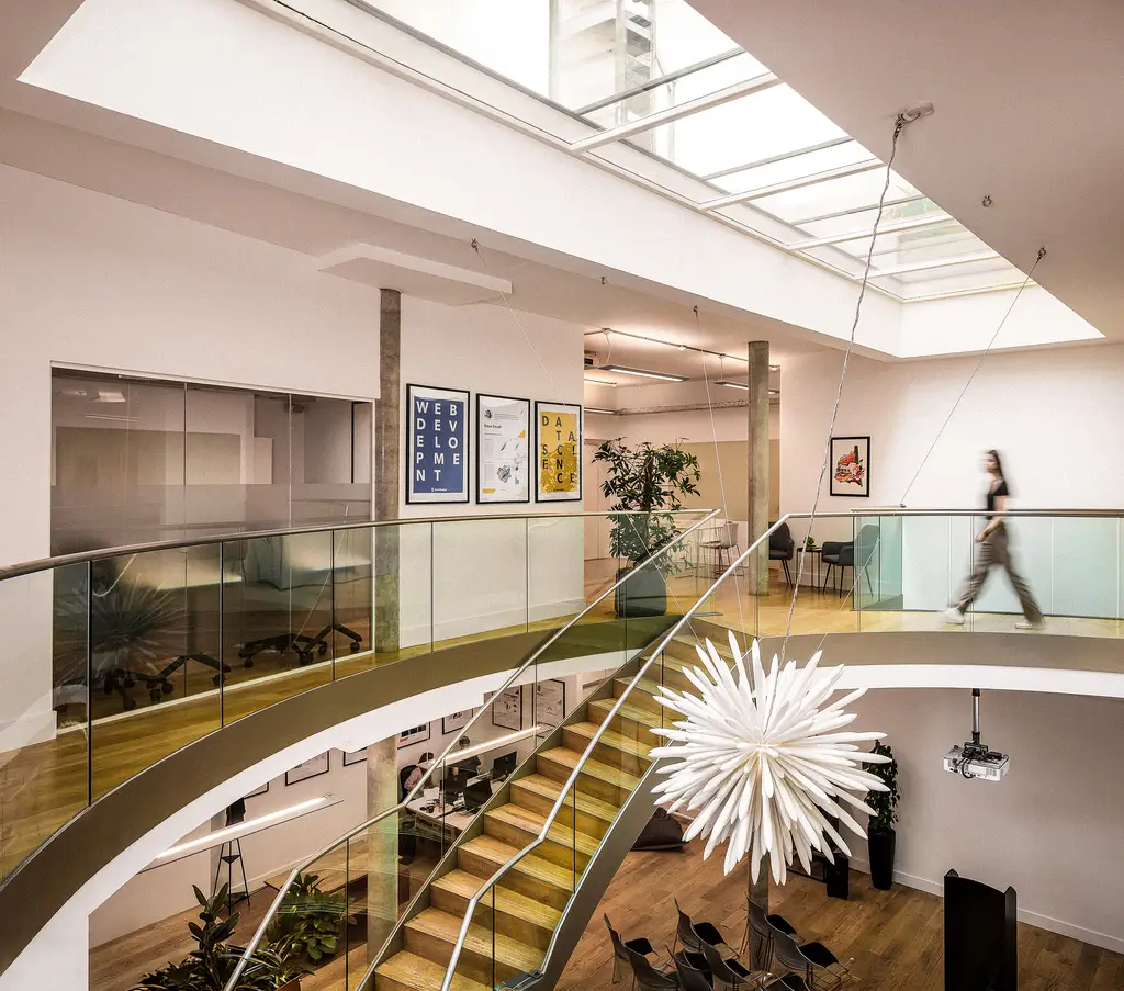 Konrad’s London office atrium with a skylight, glass balustrades and the Konrad logo on the wall