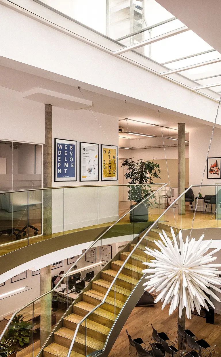 Konrad’s London office atrium with a skylight, glass balustrades and the Konrad logo on the wall