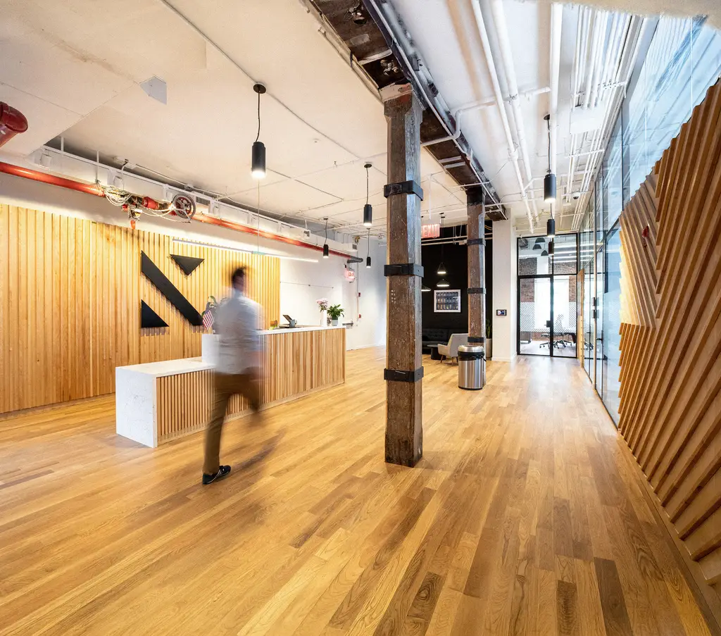Konrad’s New York office reception, with a wood-slat wall and exposed timber column