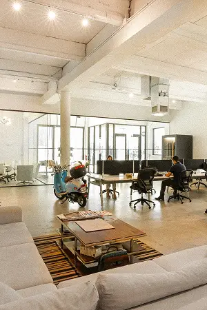 A bright loft lounge with large windows and casual seating in a Konrad office
