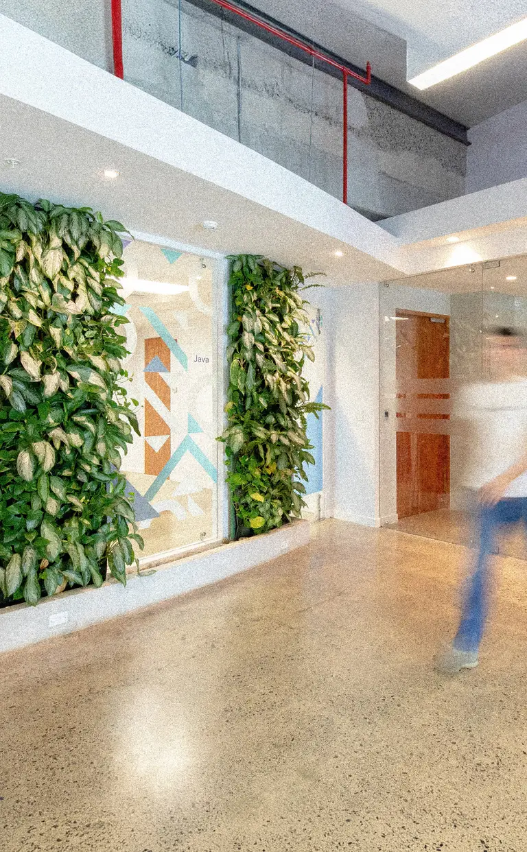 Konrad’s San José office lobby with a living green plant wall and a person walking past