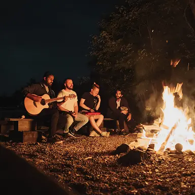 Konrad team members gathered around a campfire at night, one playing guitar