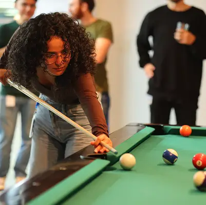 A team member leaning over a table for a game of pool