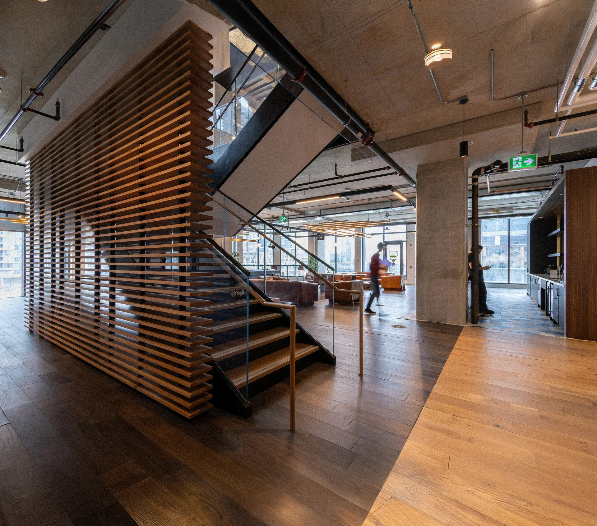Office lounge with leather armchairs and a pool table beside windows with a city view